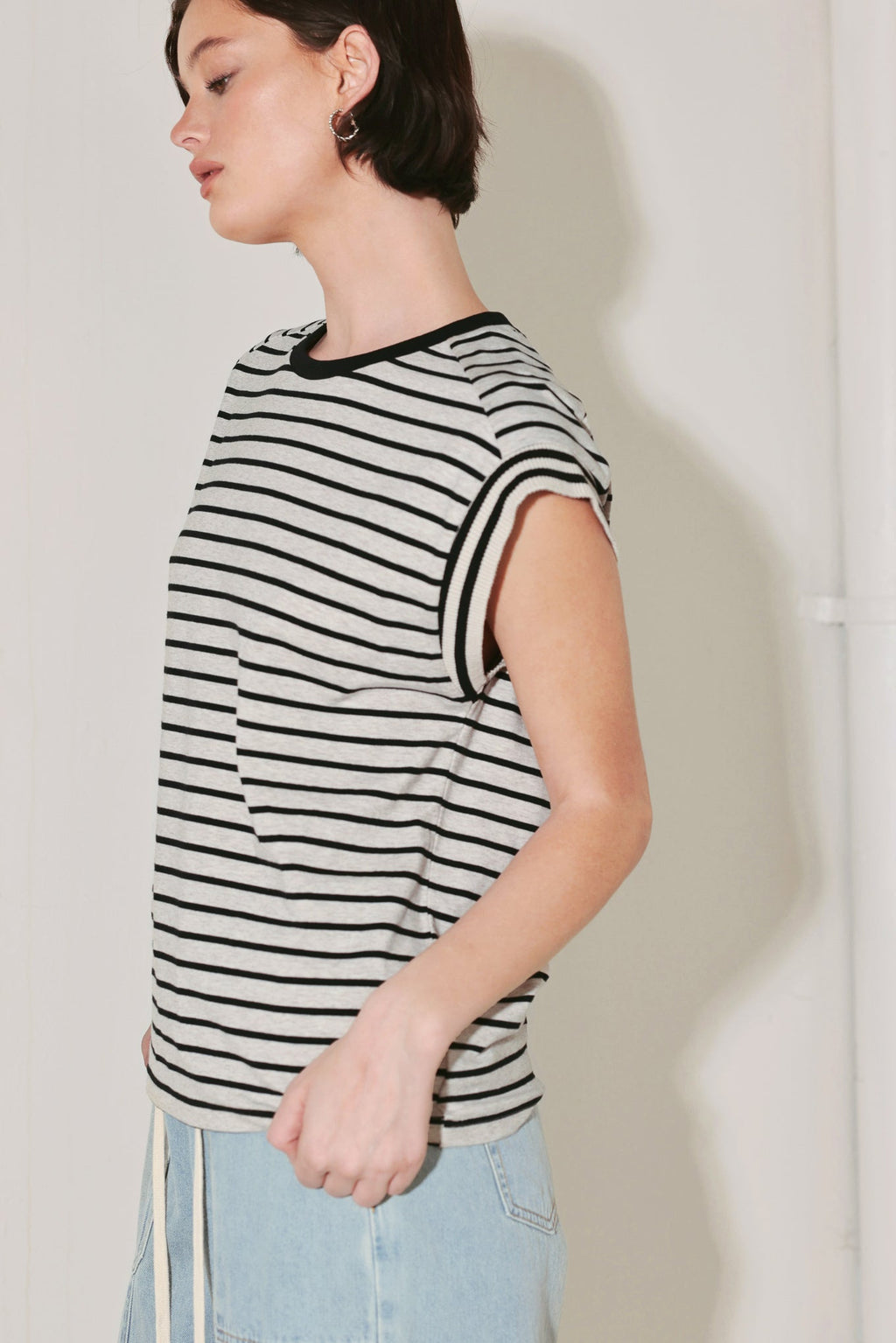 Woman wearing a black and white striped sleeveless top against a plain background