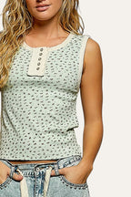 Woman wearing a light green patterned tank top against a gray background