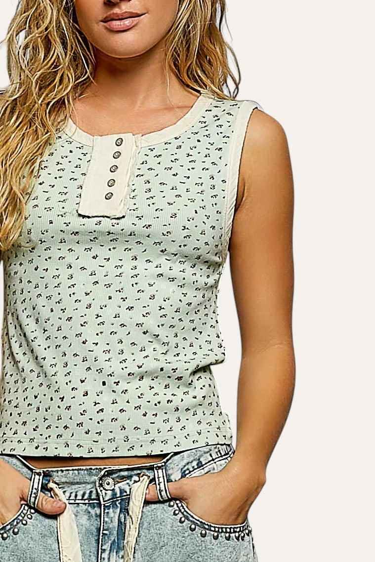 Woman wearing a light green patterned tank top against a gray background