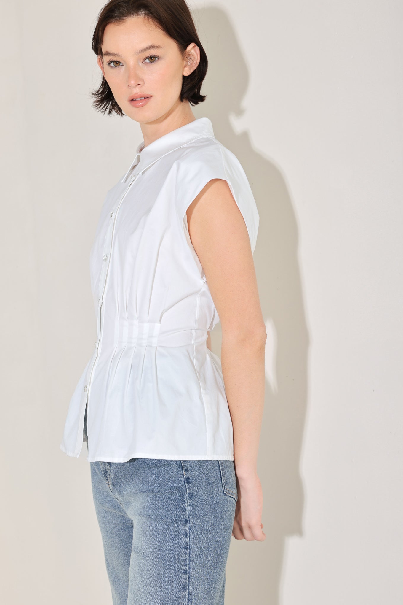 Winged meadow Side view of white cotton peplum blouse with corset waist detail