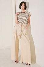 Woman wearing a striped top and beige wide-leg pants against a white background