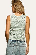 Person wearing a sleeveless top with a subtle pattern and jeans on a plain background