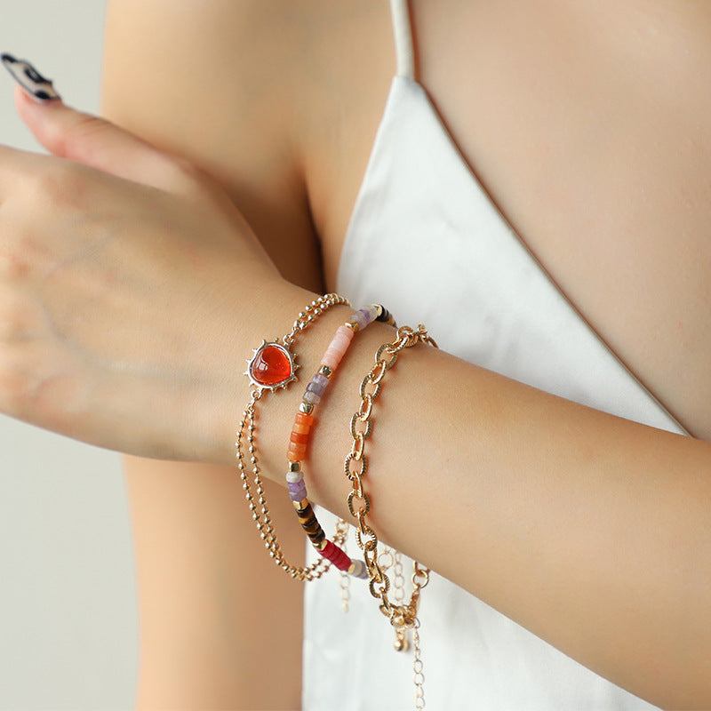 Close-up of a person's wrist wearing multiple bracelets with a neutral background Main image