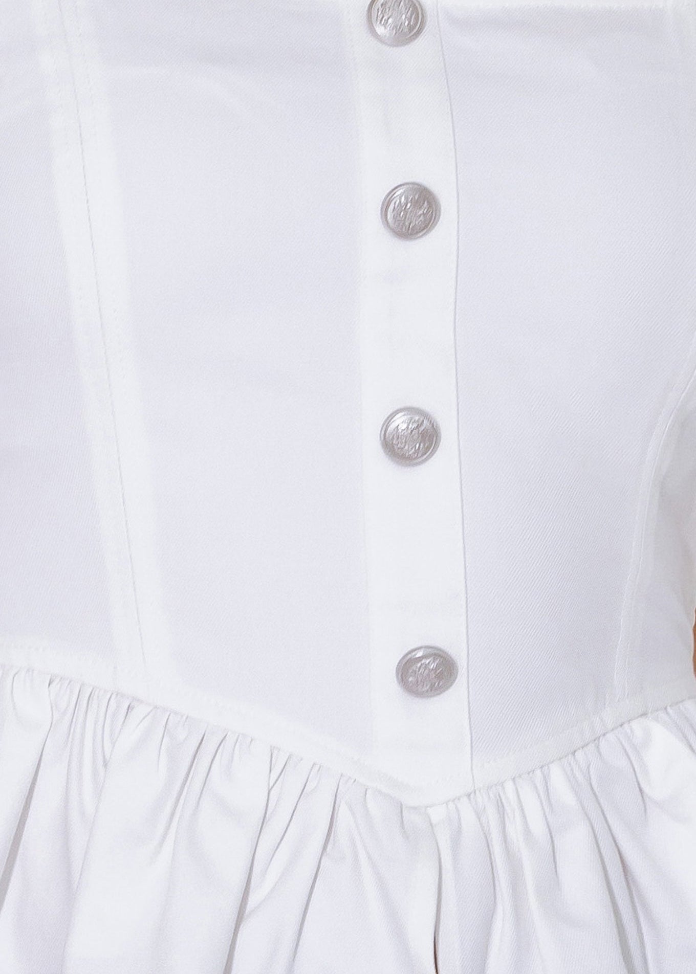 Close-up of a white dress with buttons on a white background