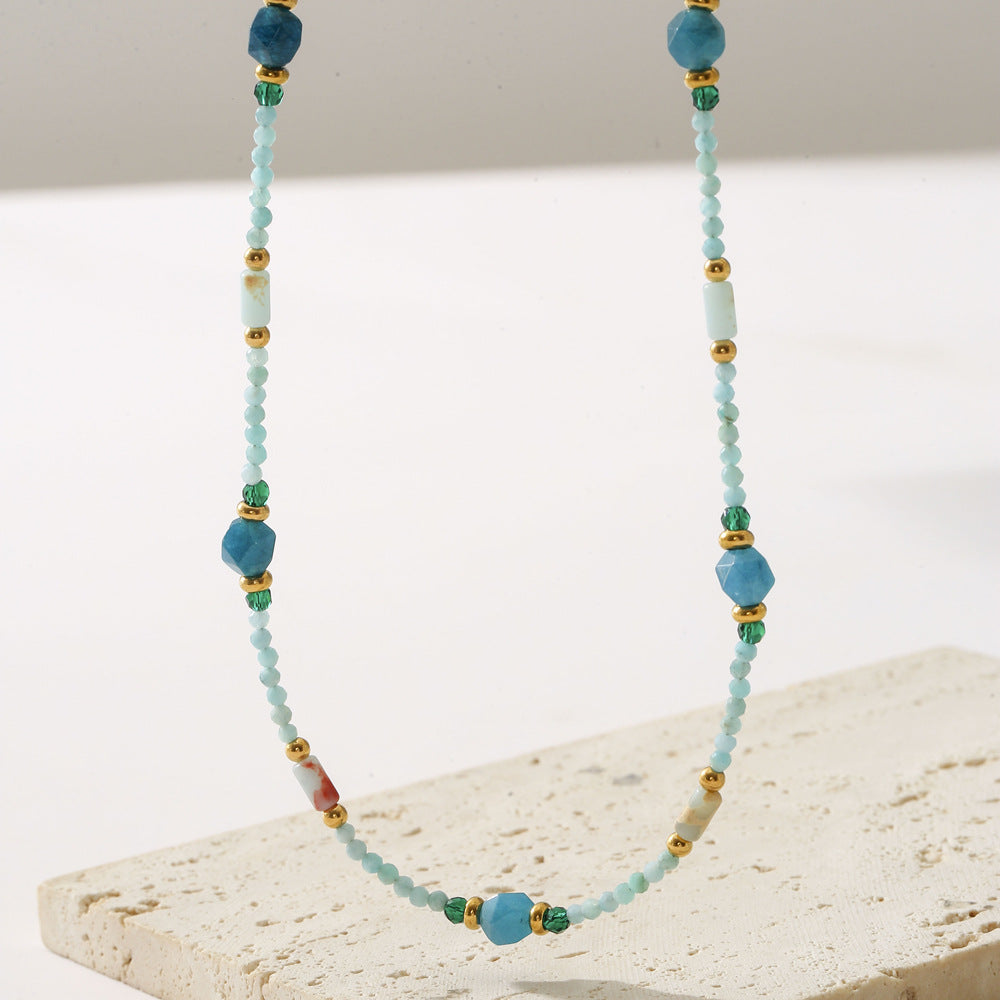 Beaded necklace with blue and green beads on a light surface