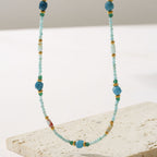 Beaded necklace with blue and green beads on a light surface