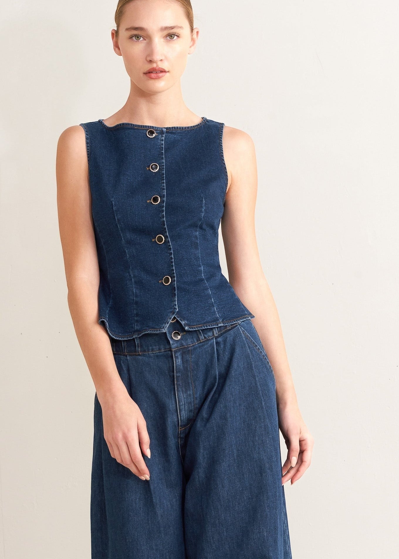 Winged Meadow Co. dark wash denim sleeveless vest with wide neckline and front button closure. Main image