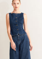 Winged Meadow Co. dark wash denim sleeveless vest with wide neckline and front button closure.