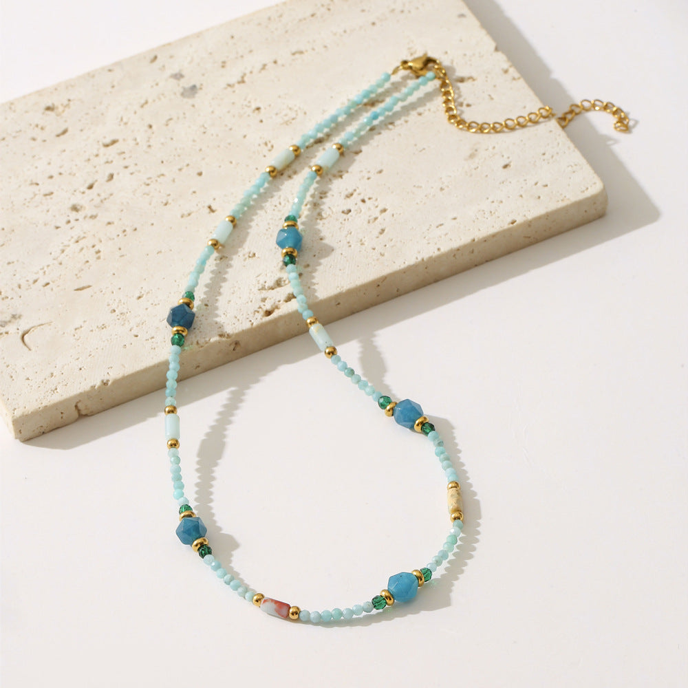 Necklace with blue beads and gold accents on a light stone surface