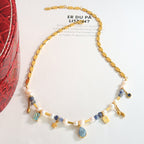 Necklace with gold chain, pearls, and colorful beads on a light background