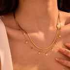 Gold necklace with small round pendants on a person's neck