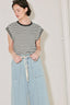 Person wearing a black and white striped top and light blue denim pants against a plain background