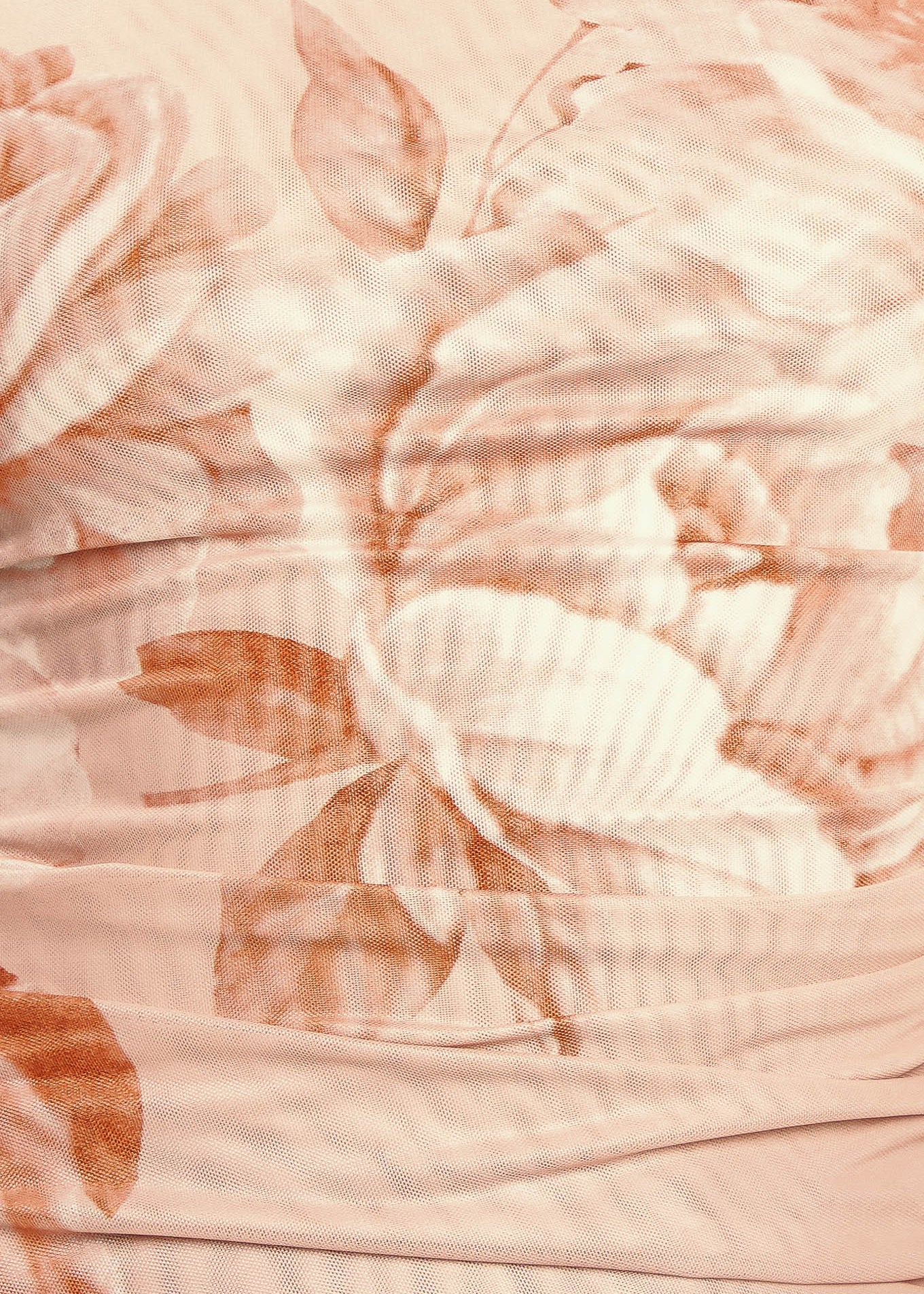 Close-up of a textured fabric with floral patterns in soft pink and peach tones.