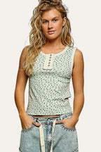 Woman wearing a patterned top and denim shorts against a gray background