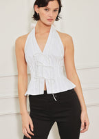 Woman wearing a white halter top with black pants against a plain background
