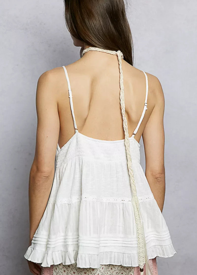 Woman wearing a white lace dress with thin straps against a gray background