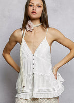 Woman wearing a white lace top with floral pants against a gray background