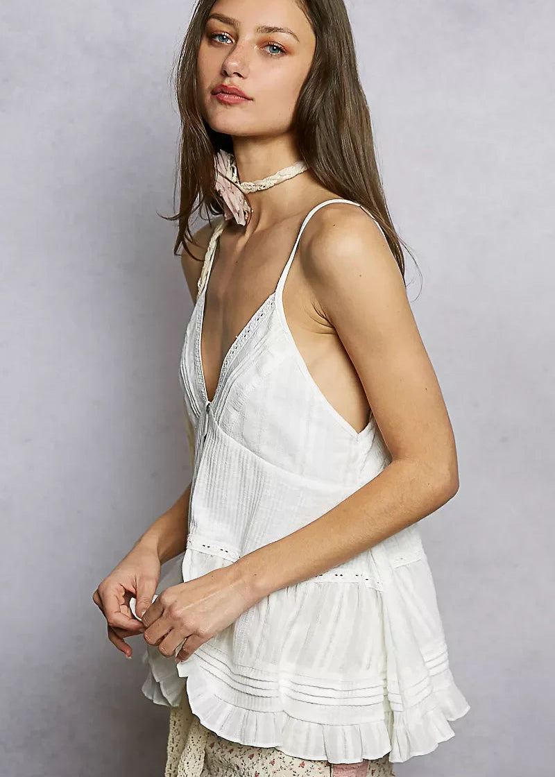 Woman wearing a white sleeveless top with a plain background