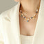 Necklace with pearls and gemstones worn by a person in a cream outfit