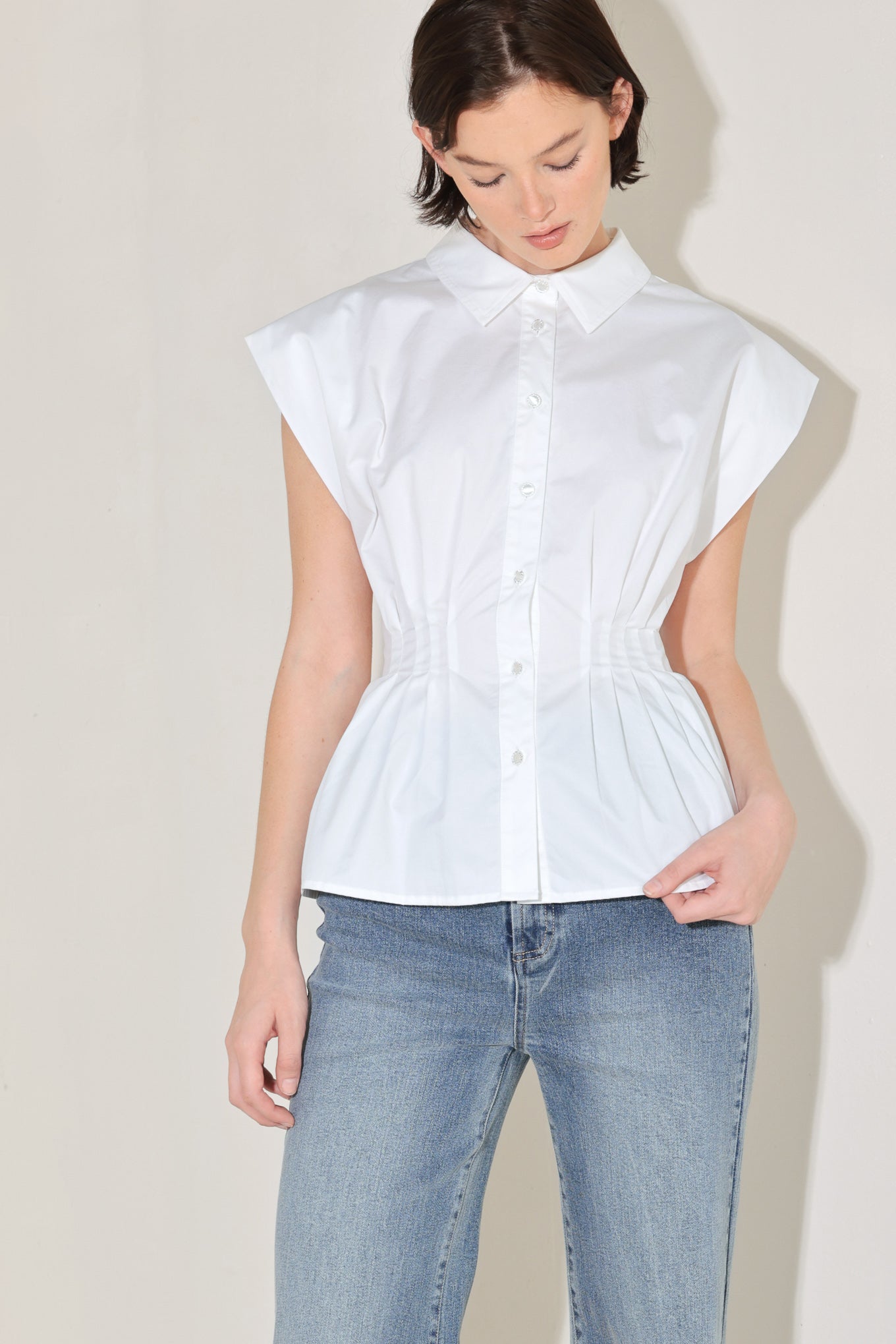 Side view of white cotton peplum blouse with corset waist detail