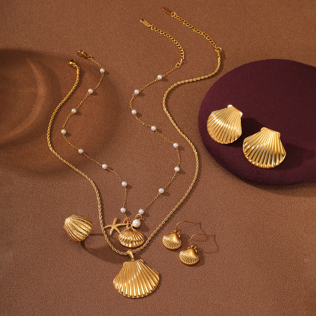 Gold necklace with shell pendants and matching earrings on a brown background
