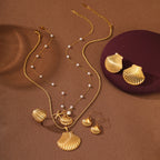 Gold necklace with shell pendants and matching earrings on a brown background