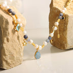 Jewelry set with pearls, gemstones, and gold accents on a stone background