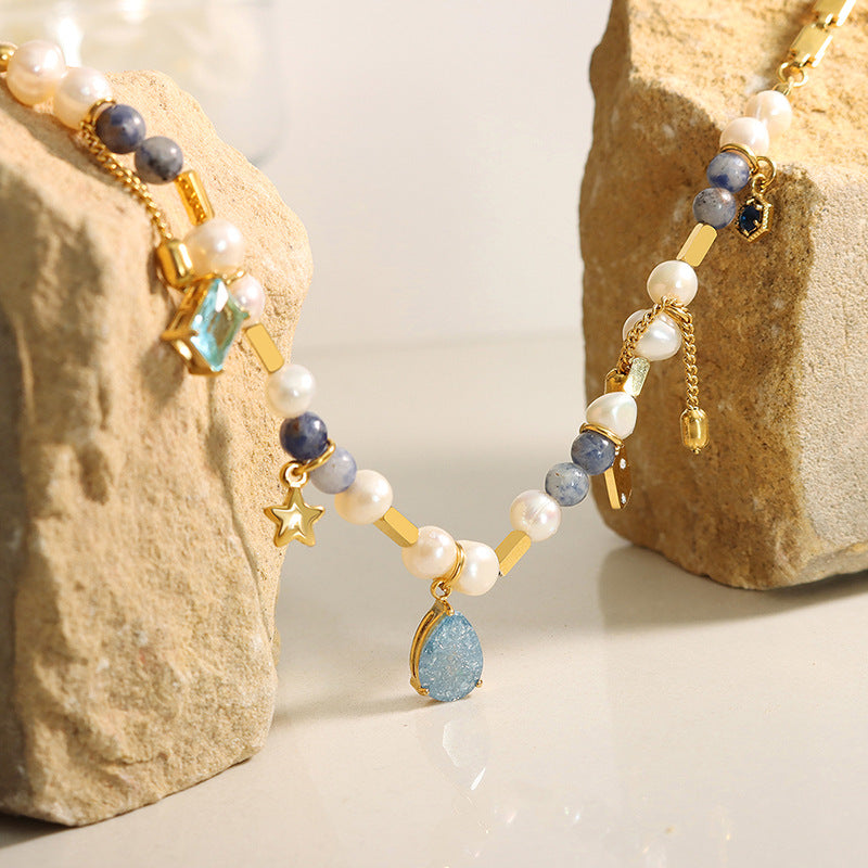 Jewelry set with pearls, gemstones, and gold accents on a stone background