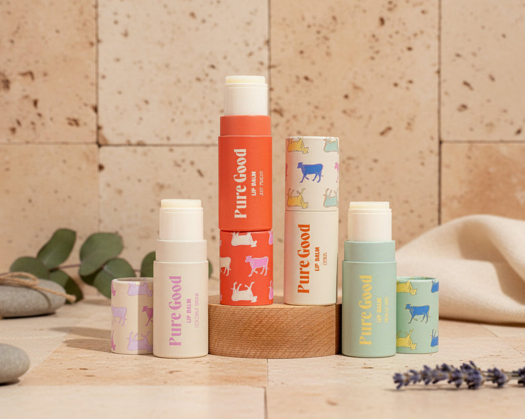 Collection of Pure Good lip balm tubes on a pink background