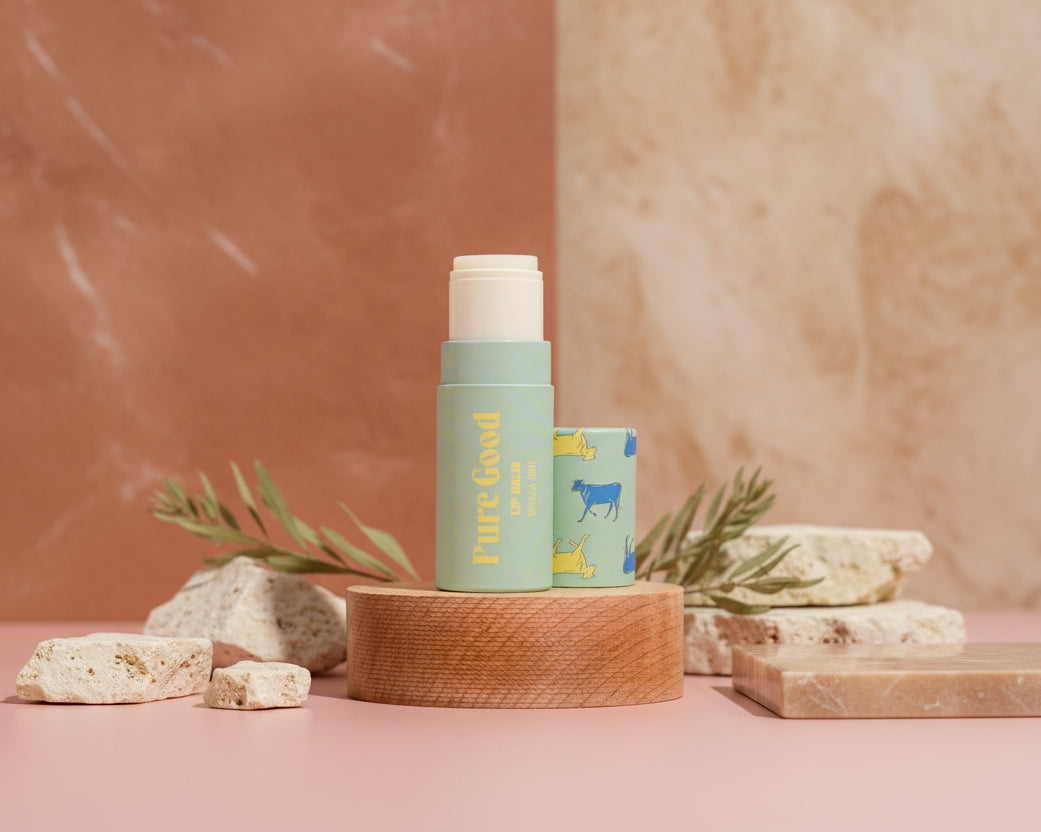 Two skincare products on a wooden stand against a pink tiled wall.
