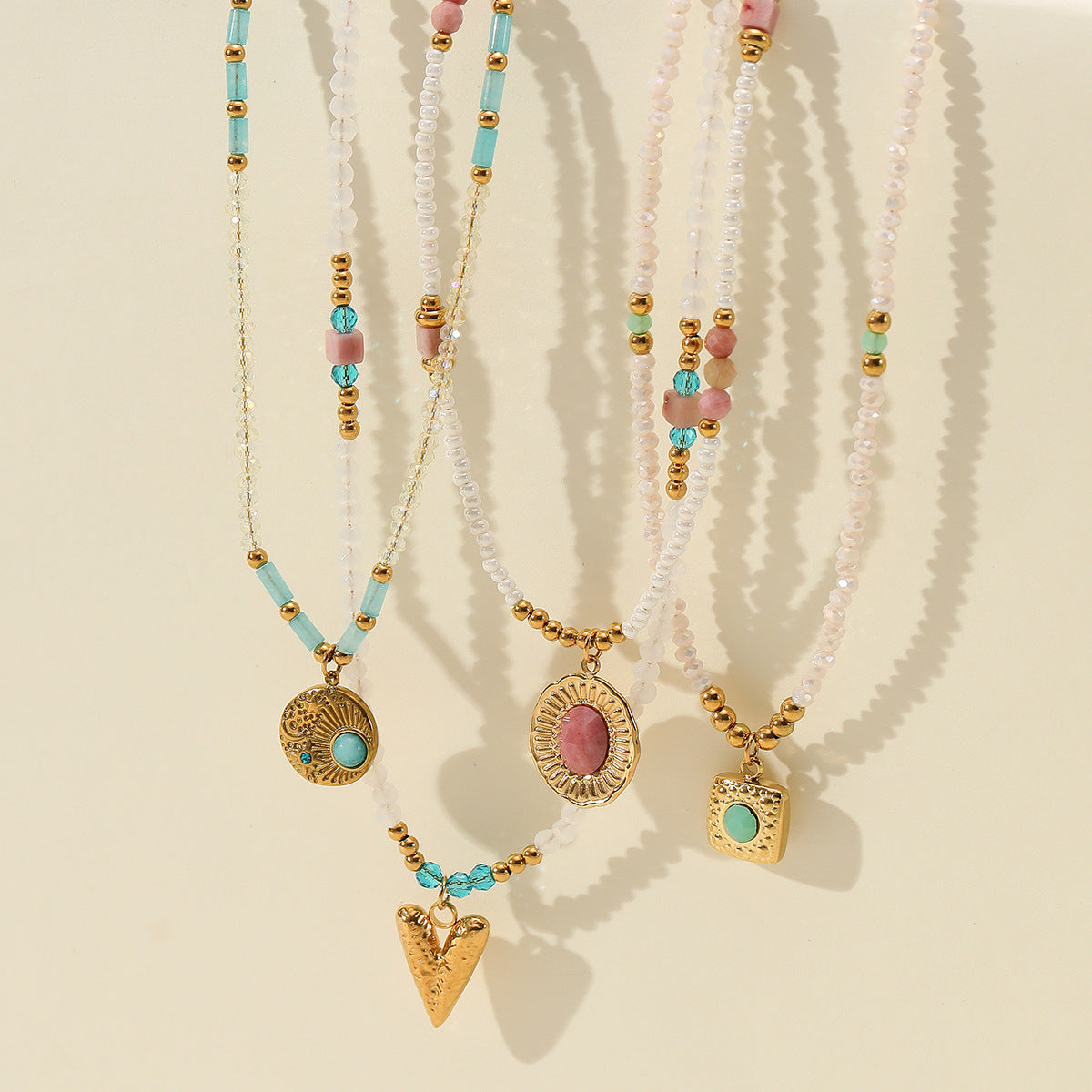 Set of beaded necklaces with gold pendants on a beige background