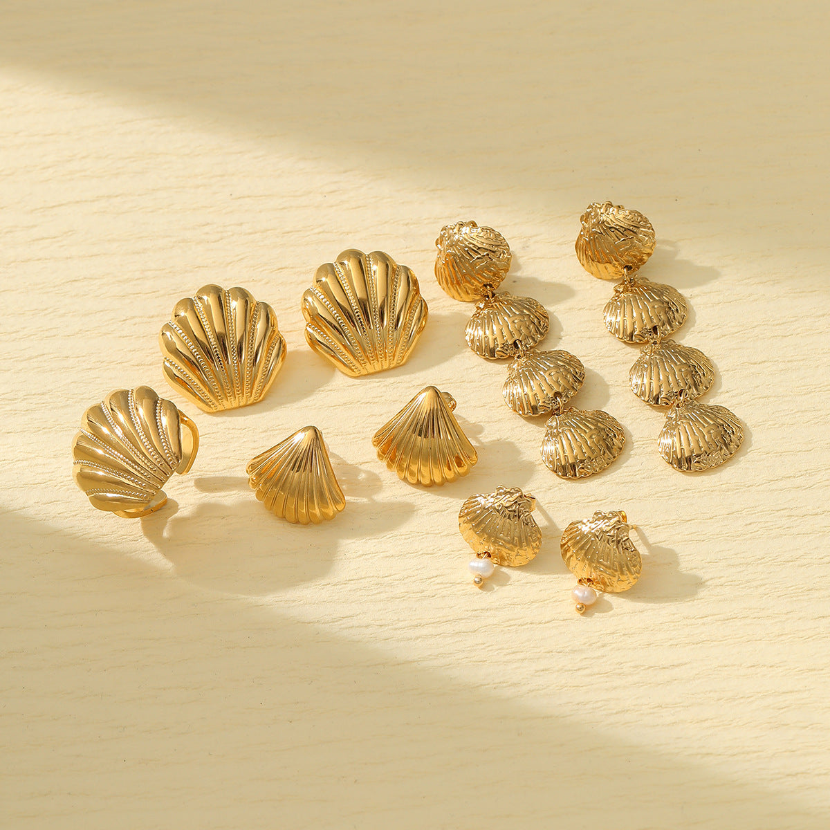 Gold shell earrings collection with stud and drop styles on neutral background