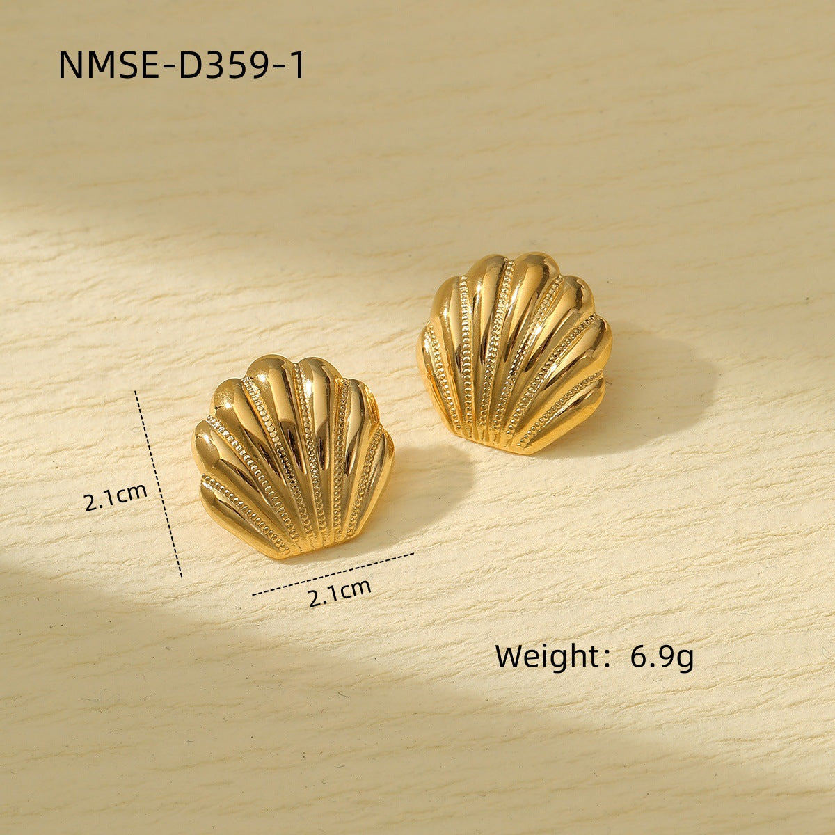Gold shell-shaped earrings on a wooden surface with measurements and weight displayed.