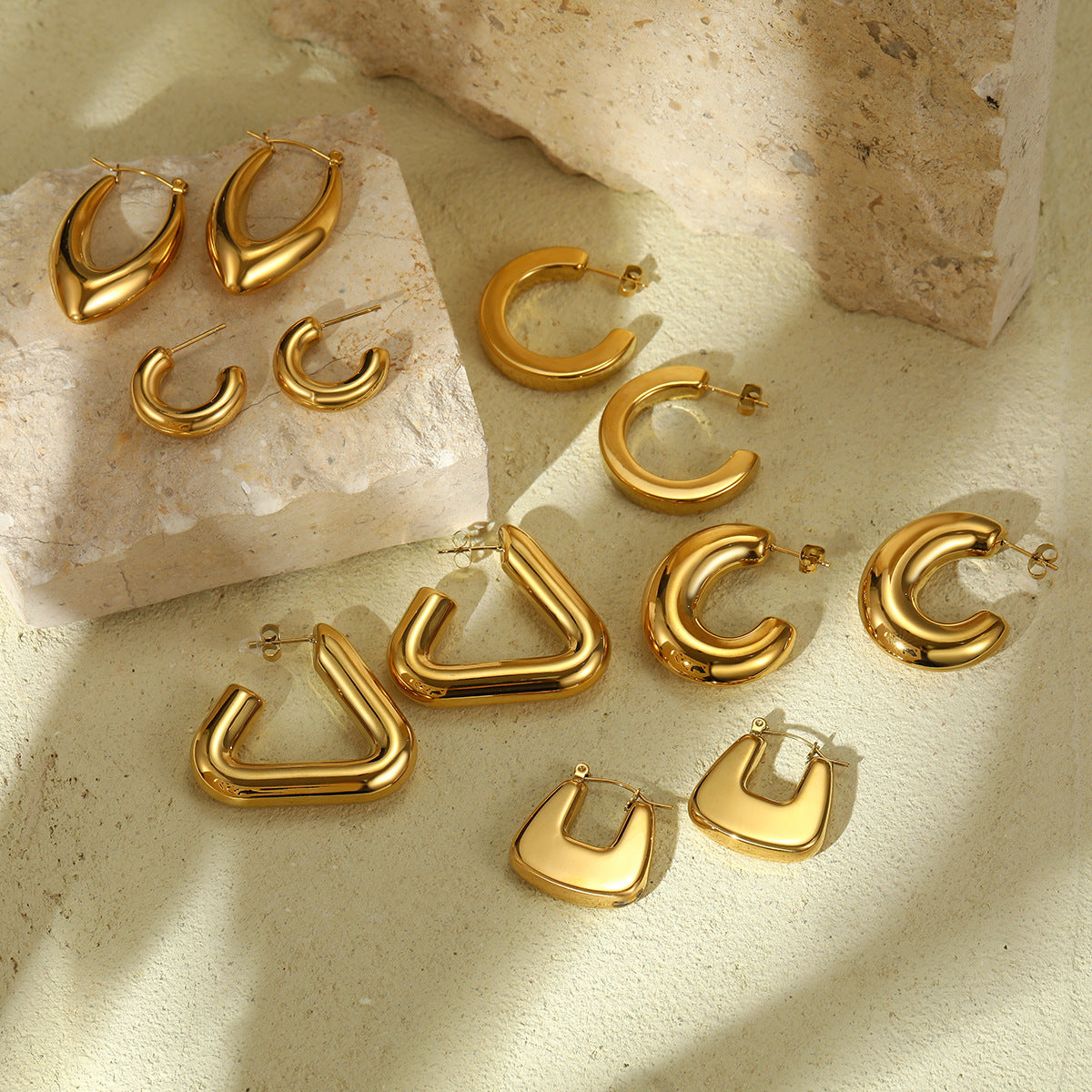 Gold hoop earrings on a textured stone surface Main image
