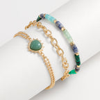Set of three bracelets with gold chain, green stone, and beaded design on a white background