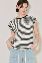 Woman wearing a black and white striped sleeveless top with light blue jeans against a plain background
