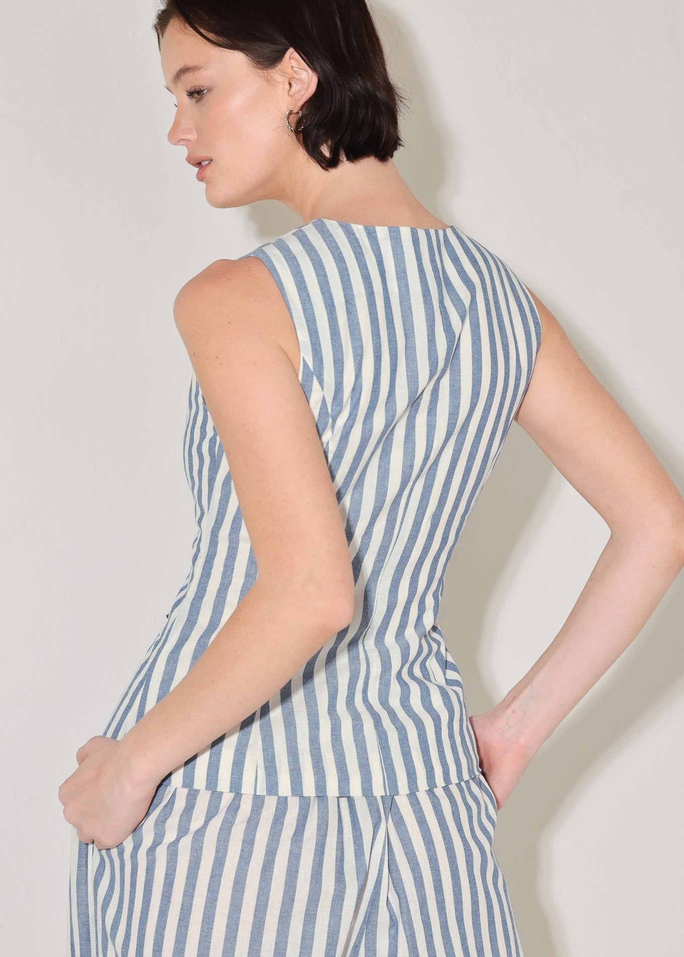 Woman wearing a blue and white striped dress against a plain background