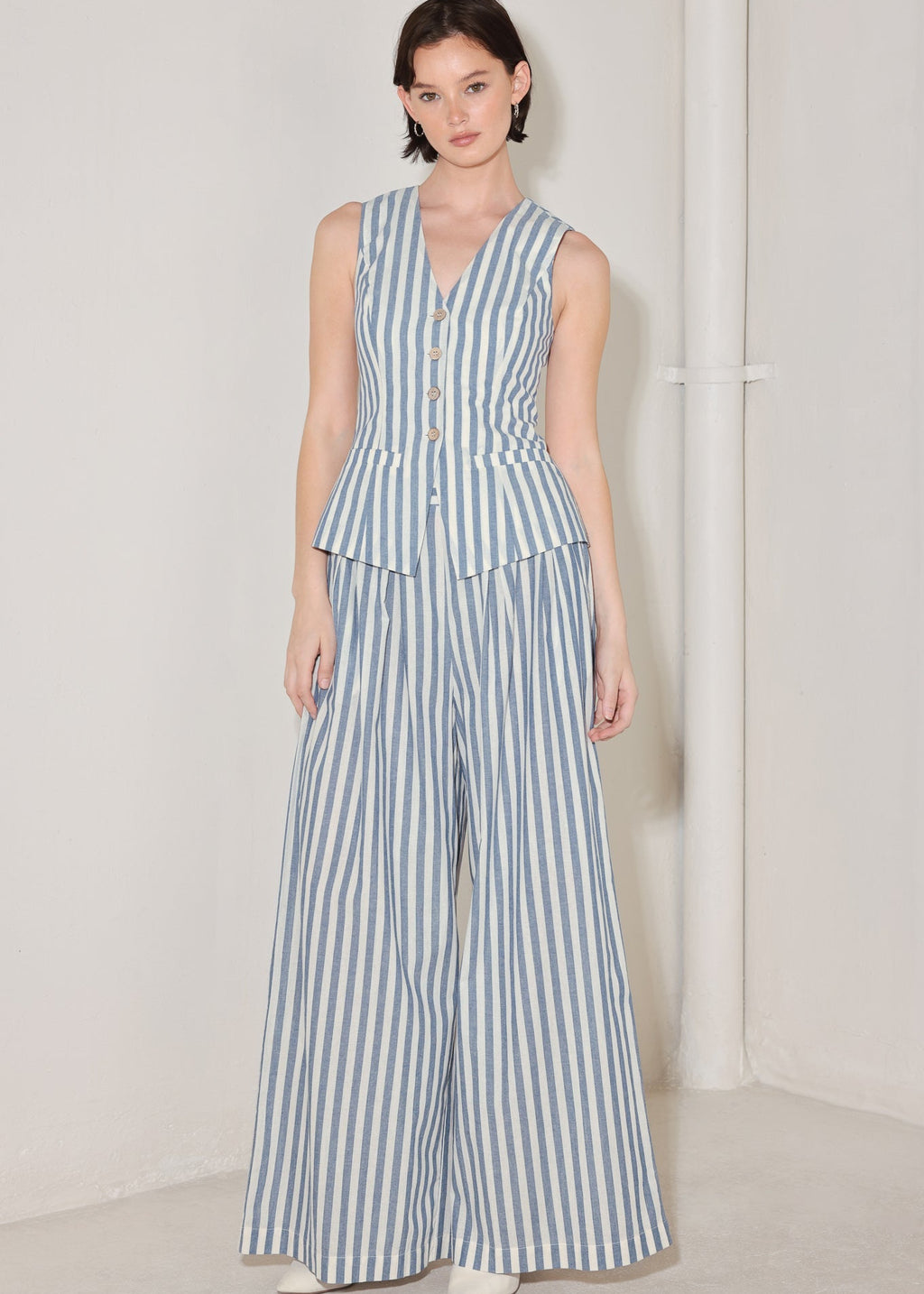 Woman wearing a blue and white striped jumpsuit on a plain background