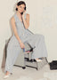 Woman in a striped jumpsuit sitting on a rolling chair, talking on a phone in an office setting.
