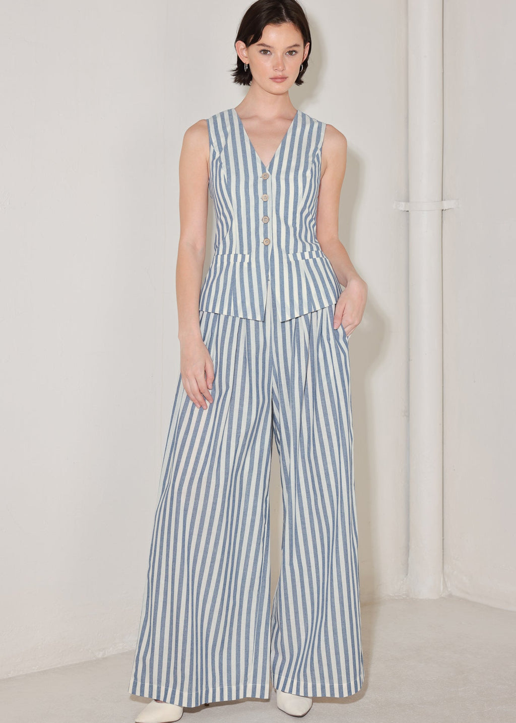 Woman wearing a blue and white striped jumpsuit on a plain background
