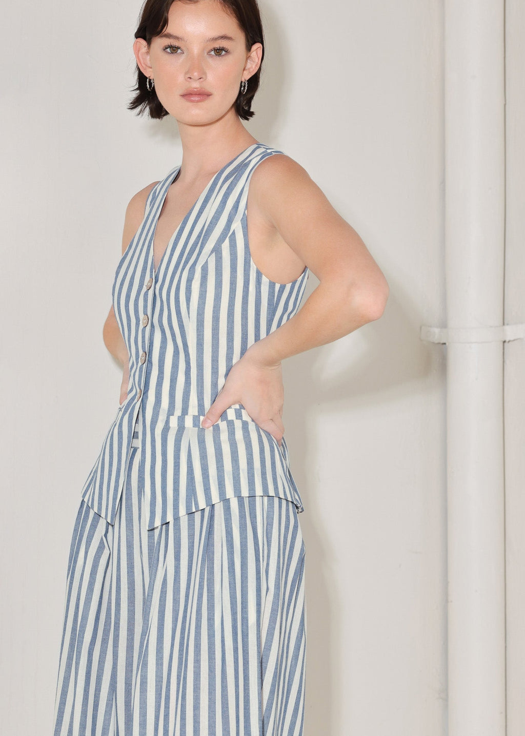 Woman wearing a blue and white striped dress against a plain background