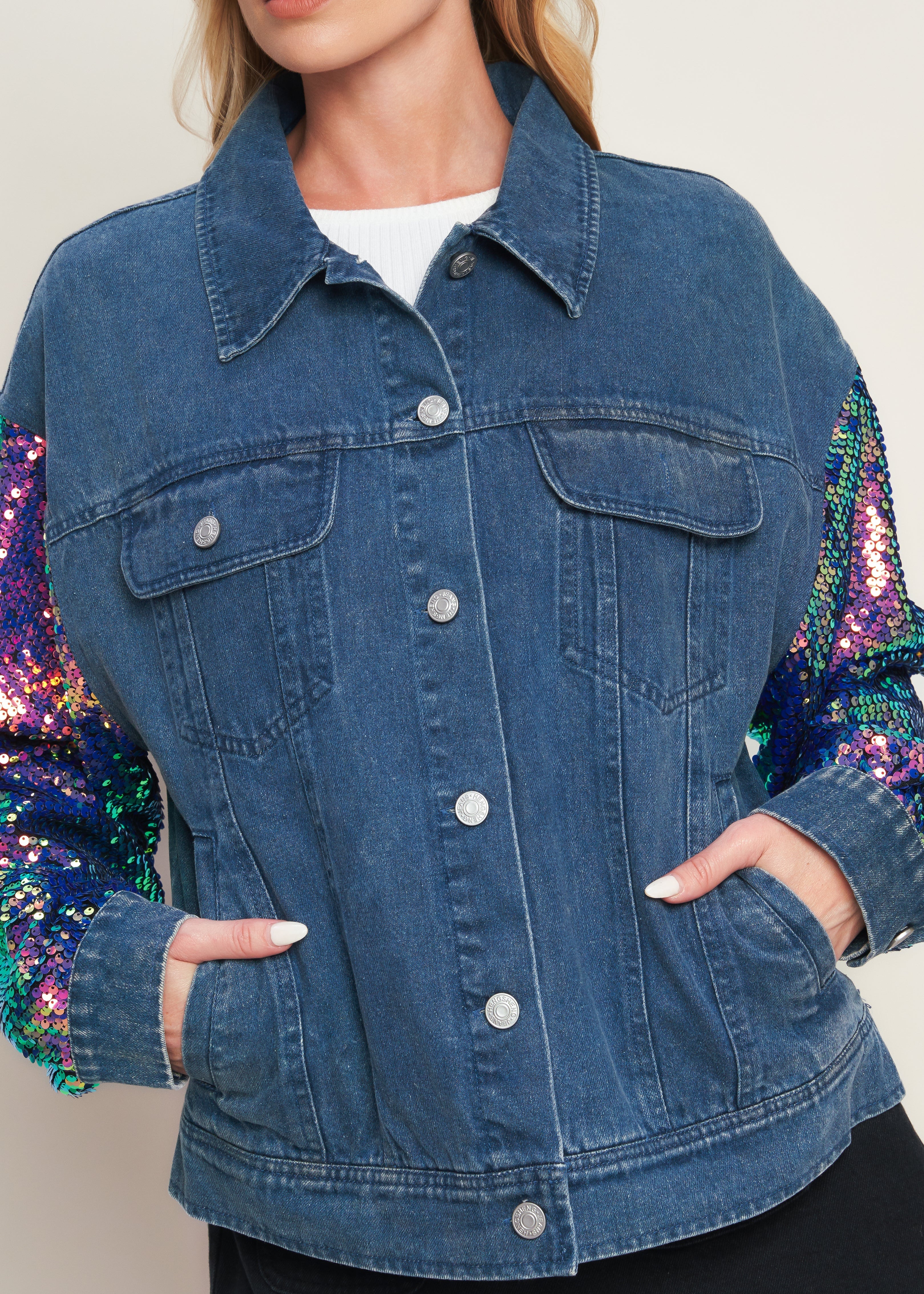 Close up of women’s washed denim jacket with colorful sequin sleeves and button front detail