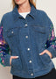 Close up of women’s washed denim jacket with colorful sequin sleeves and button front detail