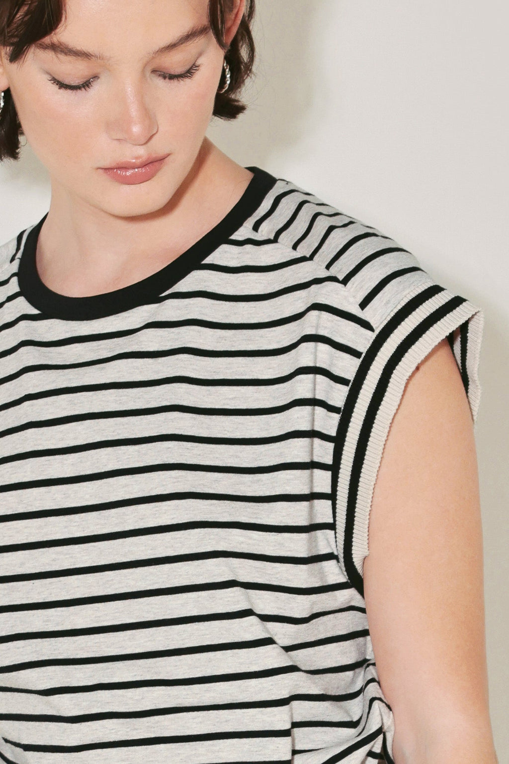 Woman wearing a black and white striped sleeveless top against a plain background