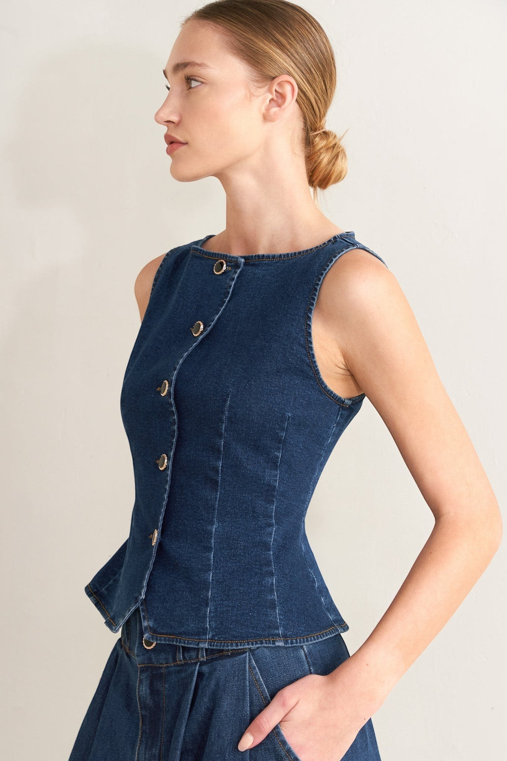 Winged Meadow Co. dark wash denim sleeveless vest top with wide neckline and gold button front closure.
