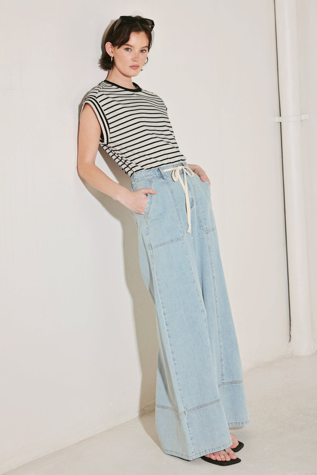 Woman wearing a striped shirt and light blue jeans against a white background