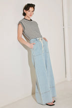 Woman wearing a striped shirt and light blue jeans against a white background