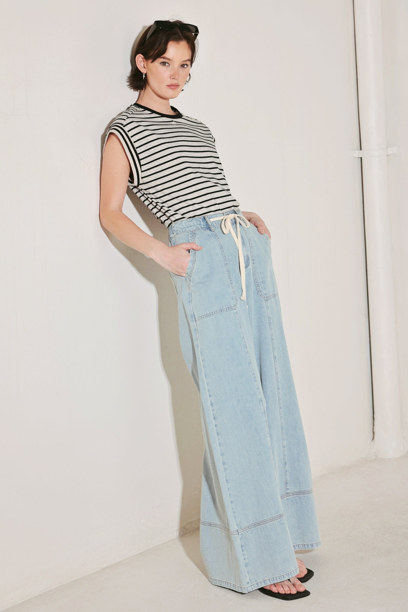 Woman wearing a striped shirt and light blue jeans against a white background